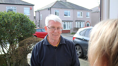 Cllr Gerry Blaikie talking to a resident at their door.